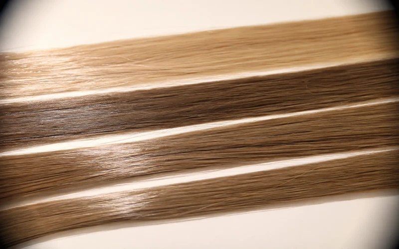 Close-up of virgin human hair strands under magnification showing intact cuticle alignment and natural shine